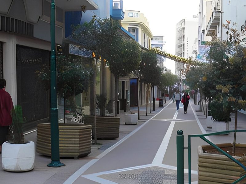 A street with people walking on the sidewalk.